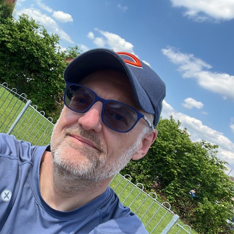 Simon Banwell ER Founder Man with glasses and a cap, smiling outdoors against a sunny sky and greenery.